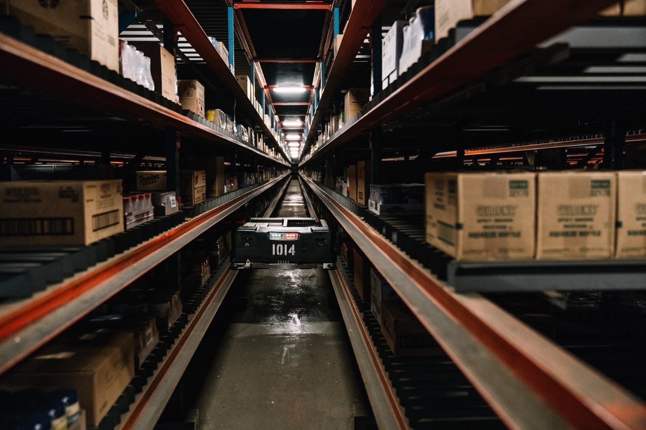 A Symbotic autonomous robot, resembling a small driverless go-cart, travels on ledges down a storage-rack aisle to pick out products in a C&S Wholesale grocery-distribution center in Newburgh, N.Y. PHOTO: MICHAEL RUBENSTEIN FOR THE WALL STREET JOURNAL